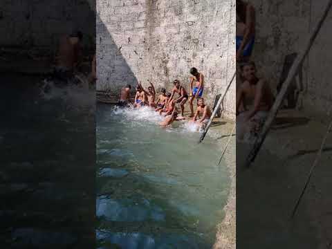 Village boys enjoying summer holidays season in deep  well by having fun with water