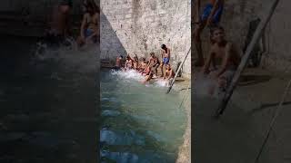 Village boys enjoying summer holidays season in deep  well by having fun with water