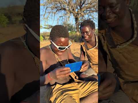 Hadzabe Tribe bushmen brothers see themselves in the mirror for the first time with sunglasses on