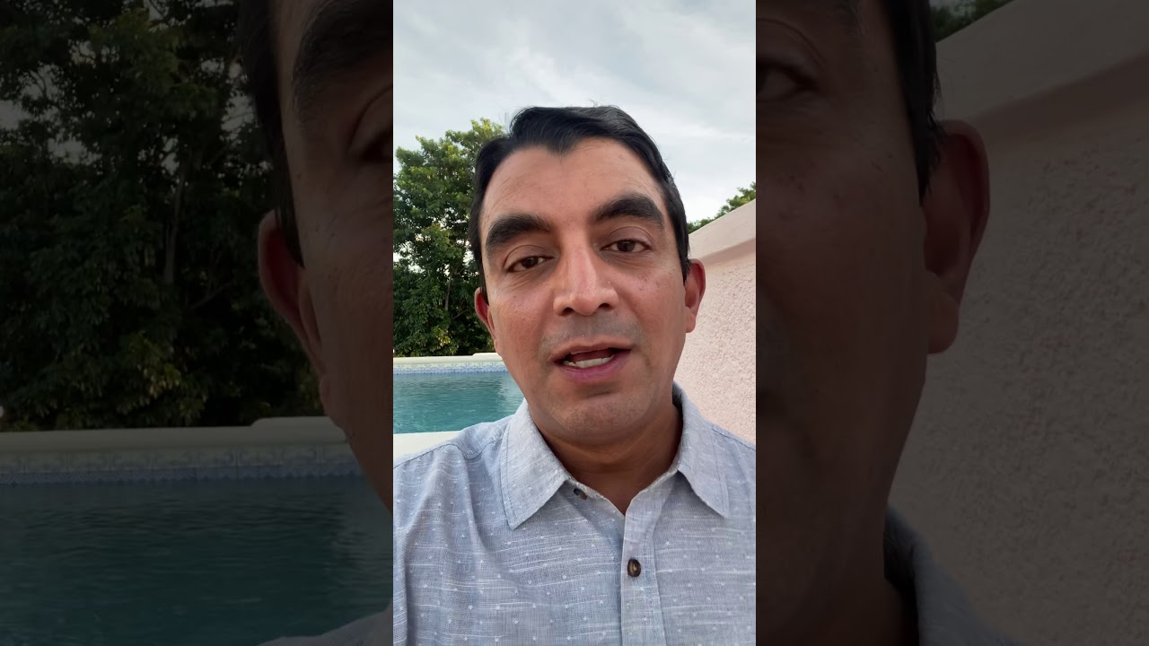 Person speaking near pool and greenery.