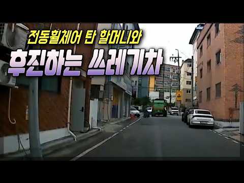 골목에서 <strong>전동휠체어</strong> 탄 할머니와 후진하는 쓰레기차
