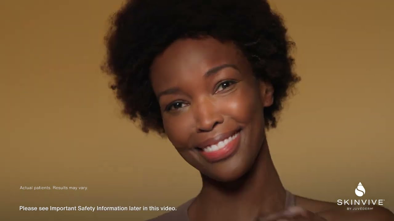 Smiling woman with curly hair against warm background.