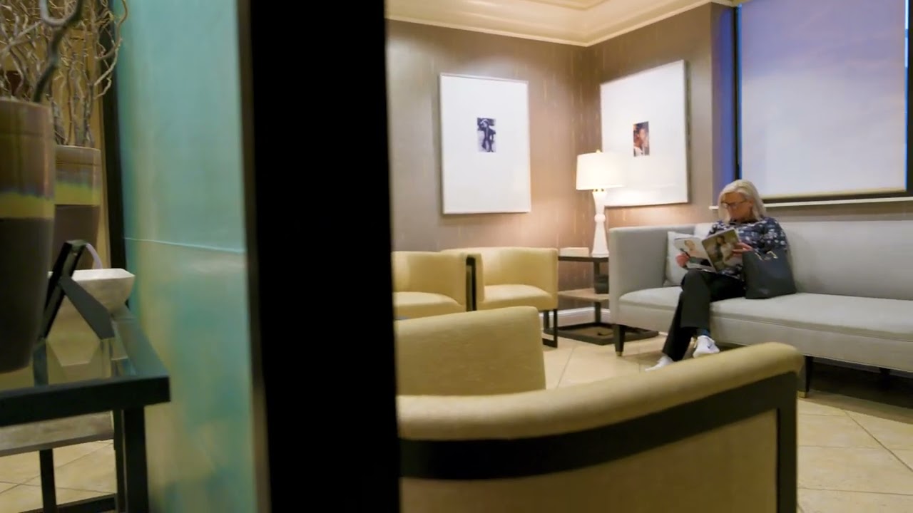 Woman reading magazine in a modern waiting area.