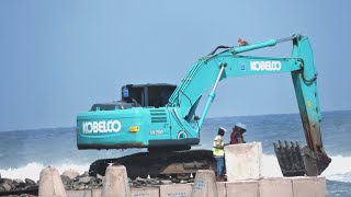 Kobelco SK200  Excavator & Cranes Work to arrange tetrapods to create awave breaker on the shoreline