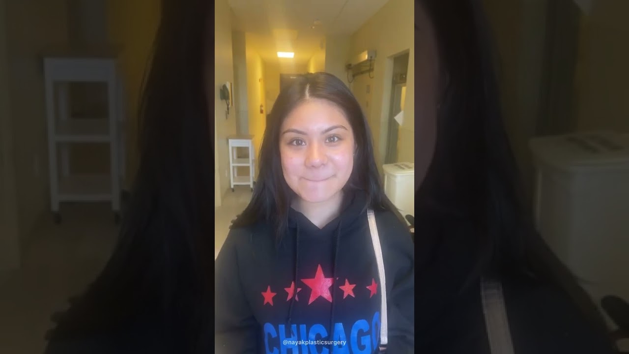 Young woman smiling in a hallway setting.