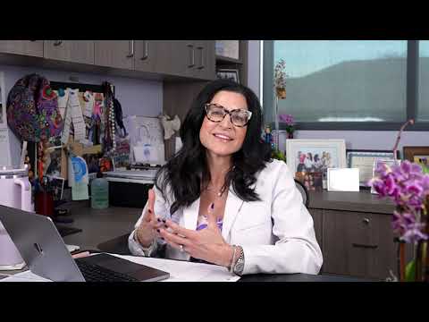Woman smiling while holding a smartphone at desk.