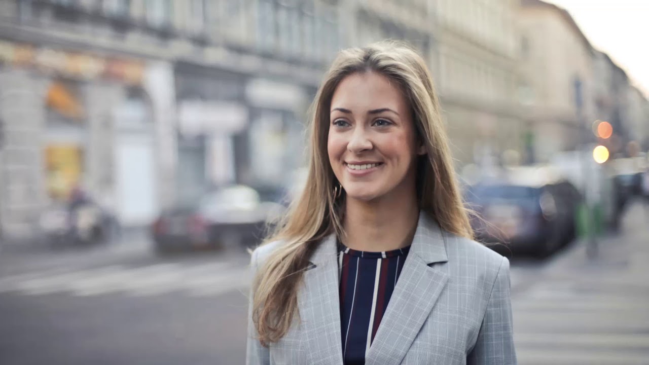 Professional woman smiling on city street.