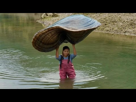 The girl got a strange clam and happily took out a big and beautiful pearl from its belly