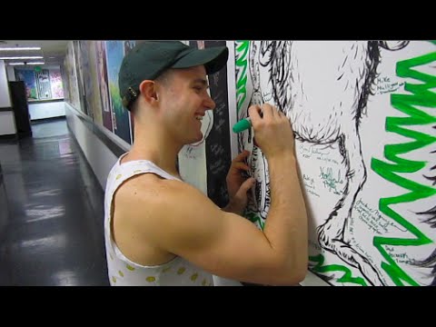 Andreas Wyder signing a giant wall poster of the Grinch as he appear in the original storybook.