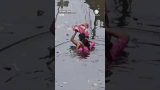 Man Holds Baby Above Floodwaters