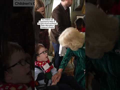 Girl surprises the Queen with a hug as children decorate Christmas tree