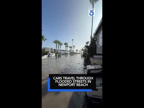 Cars travel through flooded streets in Newport Beach