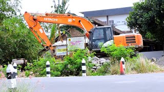 Excavator digs a hole to build a dam on the river bank with the help of a mini mixer