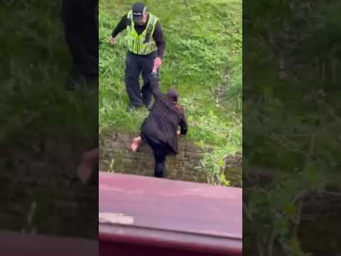 A woman gets pushed into water by a police officer