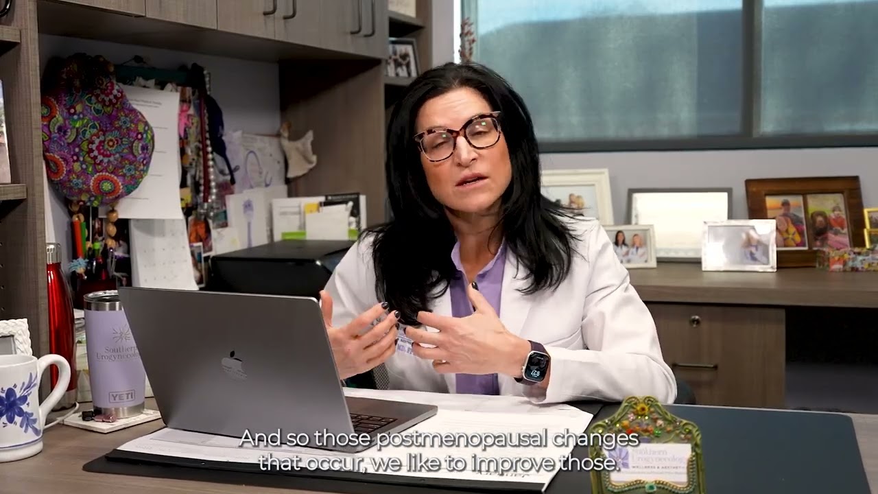 Woman smiling while holding a smartphone at desk.