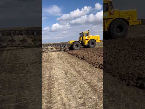 The giant yellow tractor's plough machine was stuck in the field.