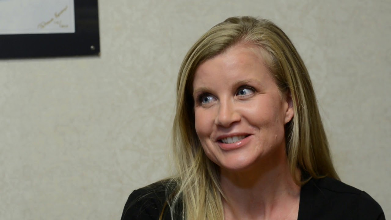 Smiling woman with long blonde hair indoors.