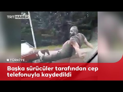 Seyir halindeki otomobilin üzerine çıktı, ayaklarıyla arızalı aracı itti