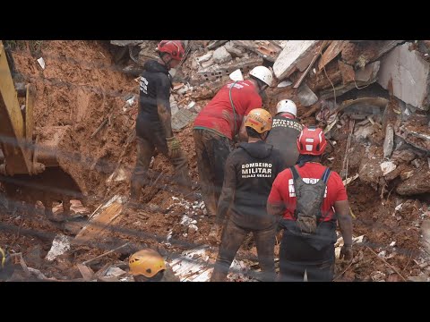 Firefighters recover a body found among debris after a landslide caused by heavy rains | AFP
