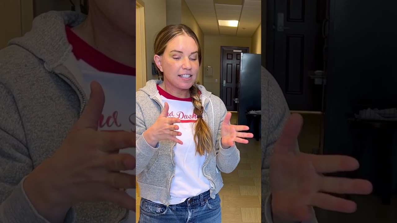 Person speaking with hands in indoor setting.