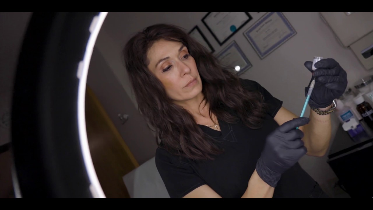 Woman preparing syringe in professional setting.