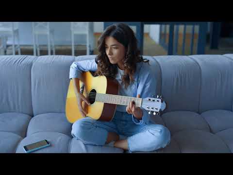 Girl Playing Guitar On Sofa