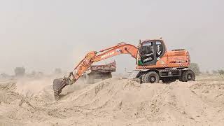 Tractors and Excavator are loading sand for Road making.