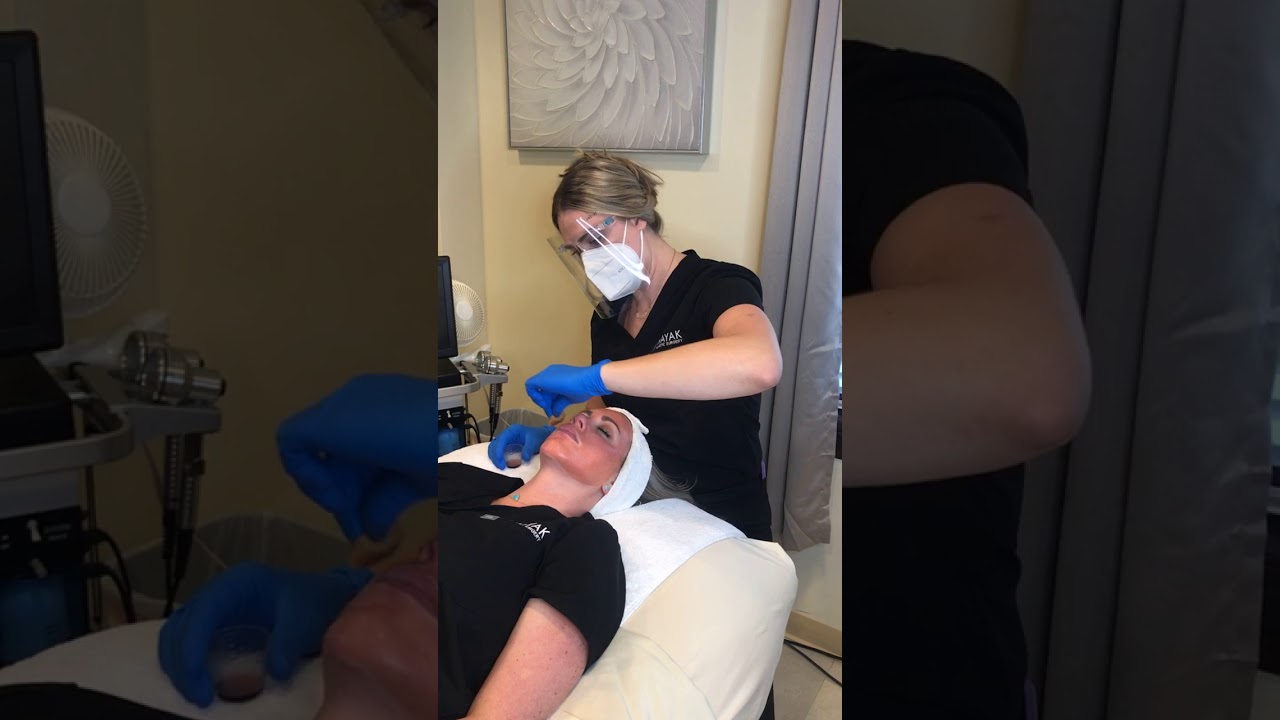 Esthetician performing a skincare treatment on client.