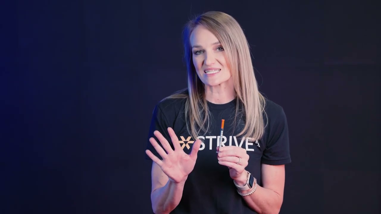 Smiling woman in STRIVE shirt against dark background.