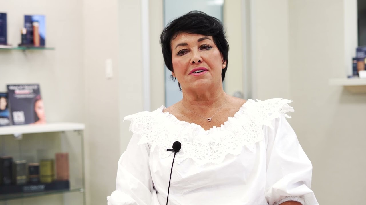 Woman in white blouse seated for an interview.