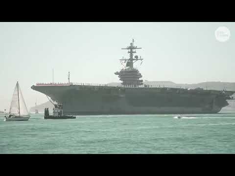 USS Abraham Lincoln arrives in San Diego harbor with sailors lined up on aircraft carrier deck