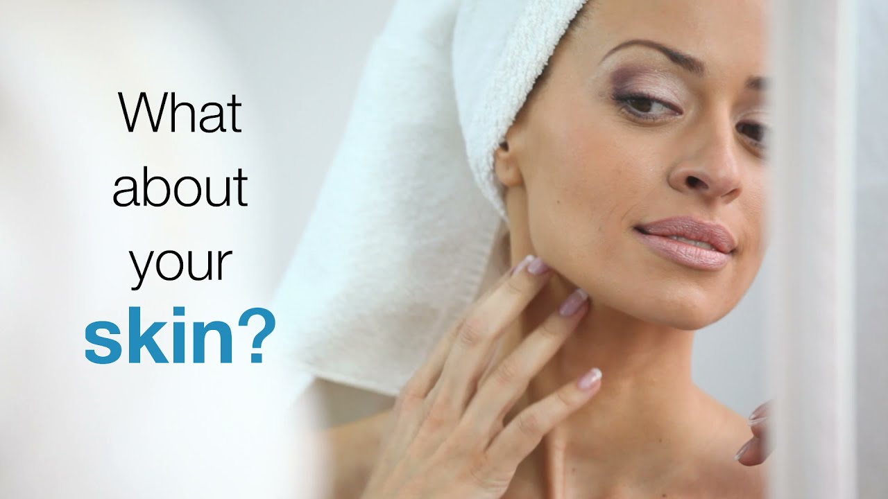 Woman examining her skin in soft lighting.