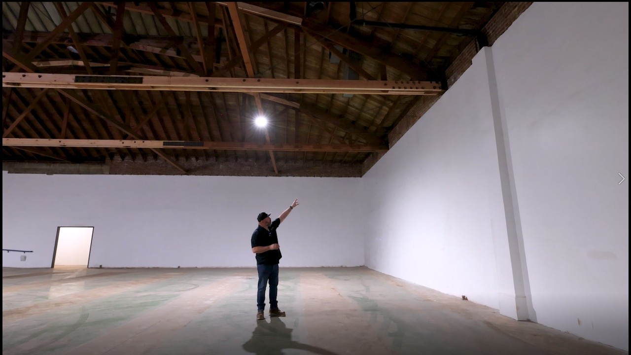 Person pointing in an empty industrial space.