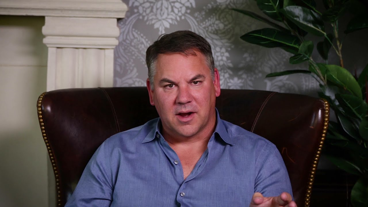 Man sitting in chair, speaking to the camera.