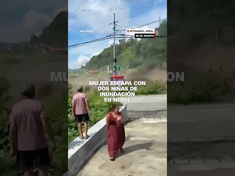Mujer escapa con dos niñas de inundación en Nepal