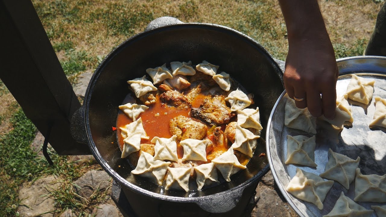 Картофельные конвертики над курицей с овощами в казане на костре