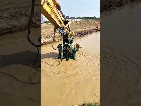 In a farm irrigation canal an excavator adjusts a hydraulic slurry pump #