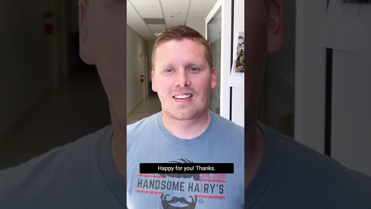 Smiling man expressing gratitude in hallway.