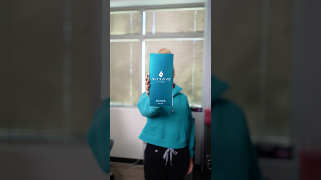 Person holding Skinvive skincare product in office.
