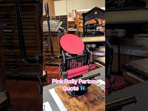 Print making a quote by Dolly Parton and a butterfly in dark pink ink with a tabletop printing press