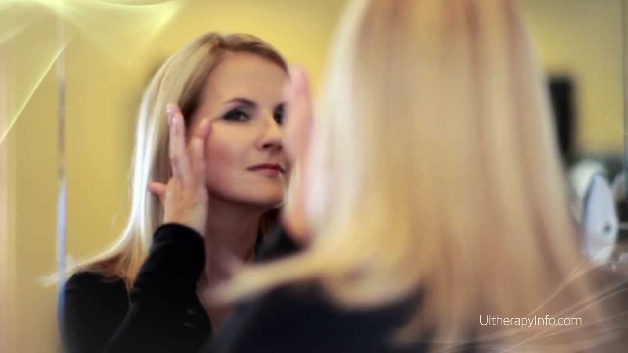 Woman applying skincare in front of a mirror.