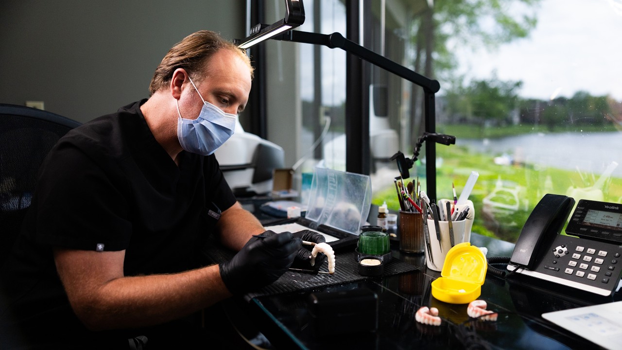 Dentist working on dental prosthetics in office.