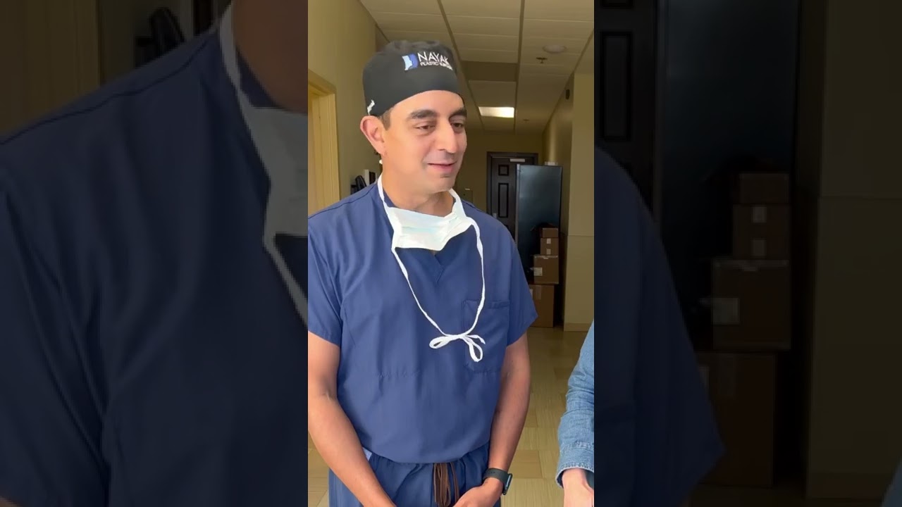 Doctor wearing scrubs and surgical mask, smiling.