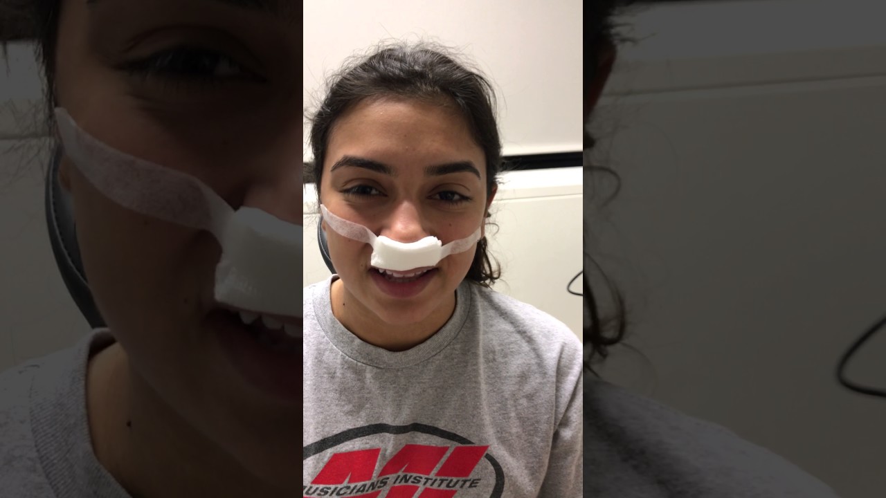 Person with bandages on nose smiling.