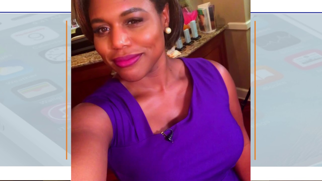 Woman smiling, wearing purple dress, taking selfie.