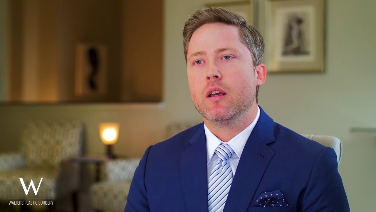 Man in a suit speaking in an office setting.