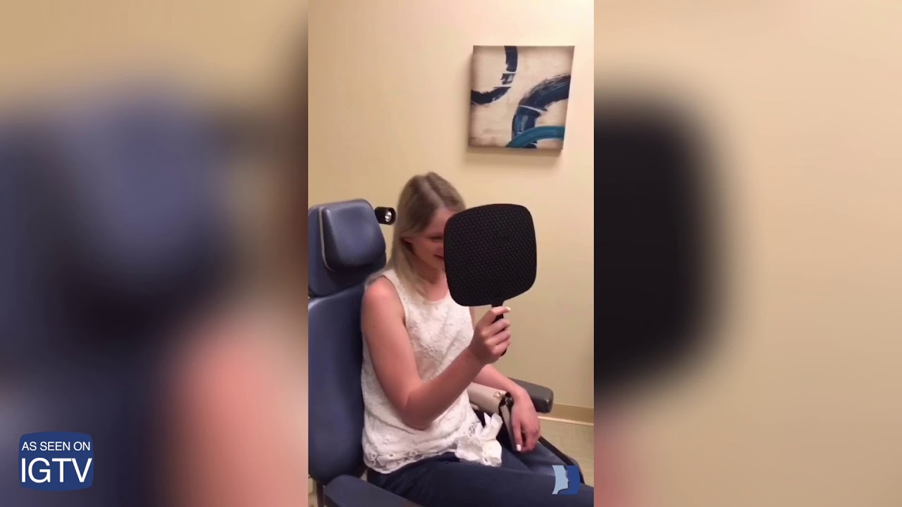 Young woman looking into a mirror in clinic.