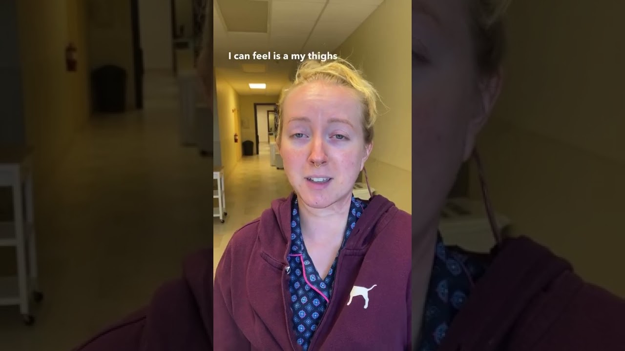 Person speaking in an indoor hallway setting.