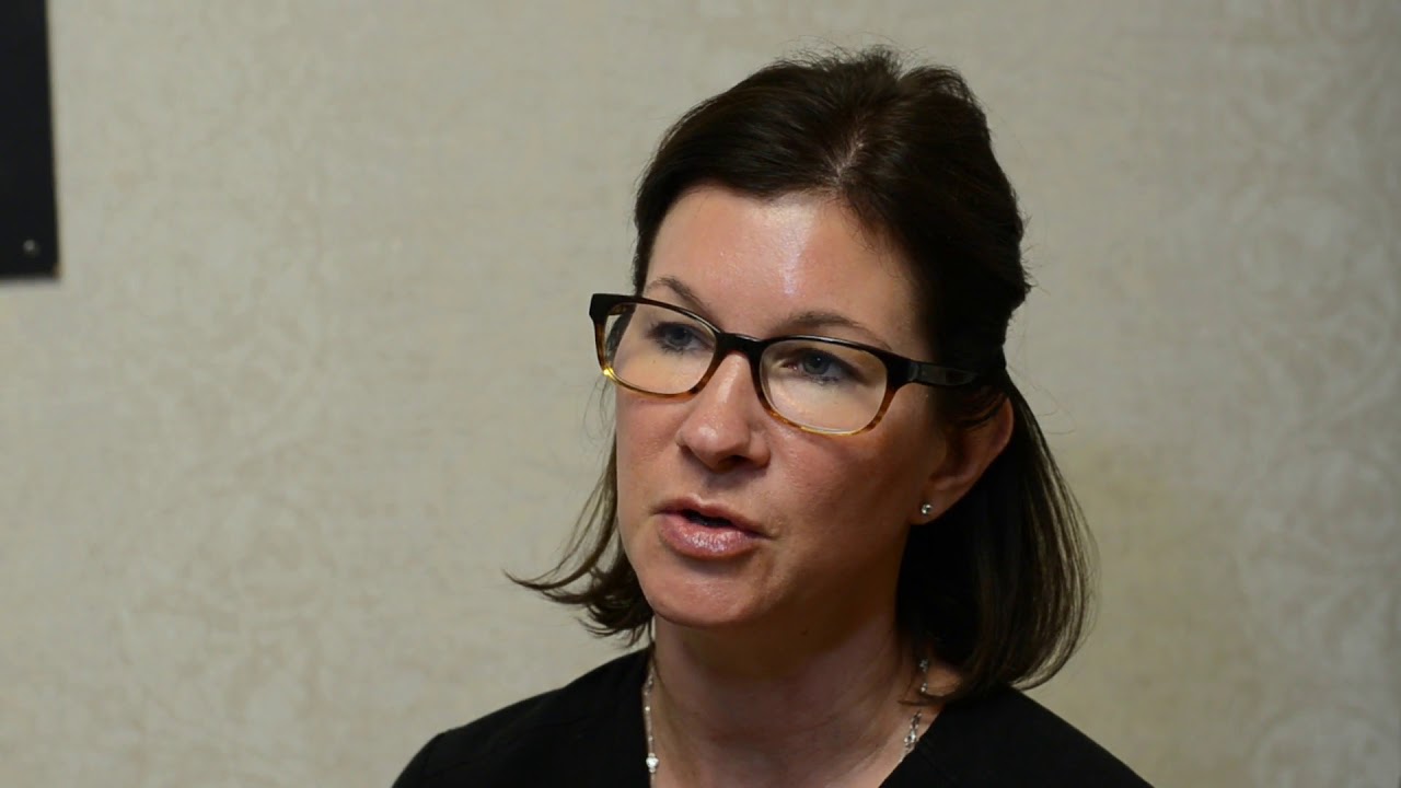 Woman speaking in interview setting with glasses.