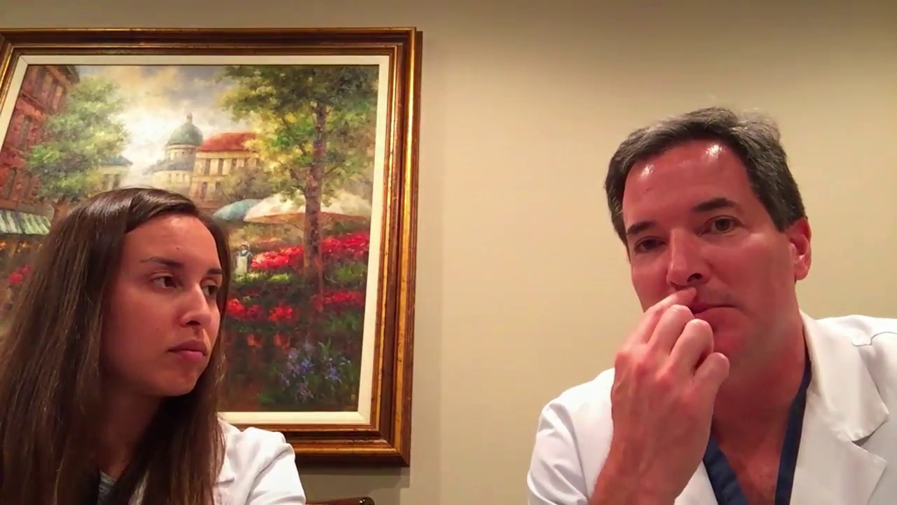 Two people discussing in front of a painting.